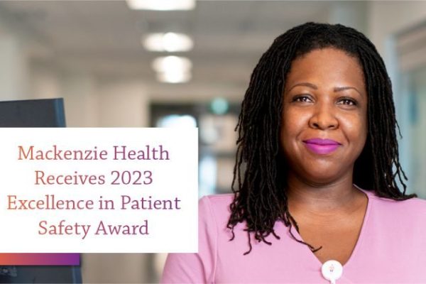 Female hospital worker, wearing pink, posing in a hospital hallway, with text over image reading, Mackenzie Health Receives 2023 Excellence in Patient Safety Award.