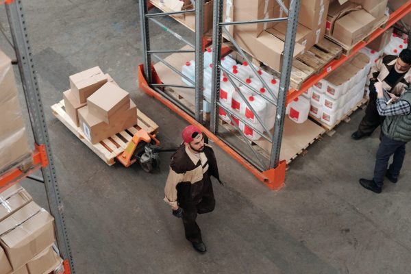 distribution logistics warehouse; male worker pulling a dolly with boxes