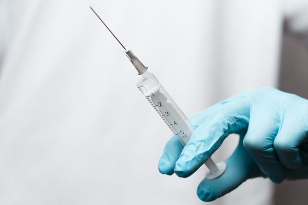 Nurse with a syringe in the hands of a medic wearing blue gloves