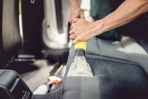 Professional using steam vacuum for draining stains to detail car