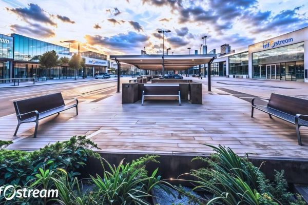 Modern and Urban Technology and Innovation Campus with outdoor employee square with benches, a wooden deck, a covered seating area, and buildings with "Infostream" logos under a cloudy sky.