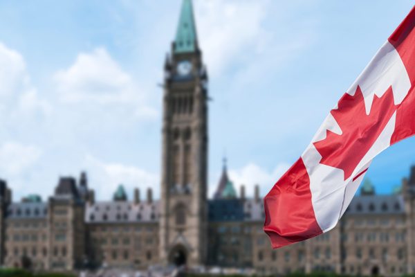 Canadian flag waving with Parliament Buildings hill in the background Ottawa,Ontario, Canada