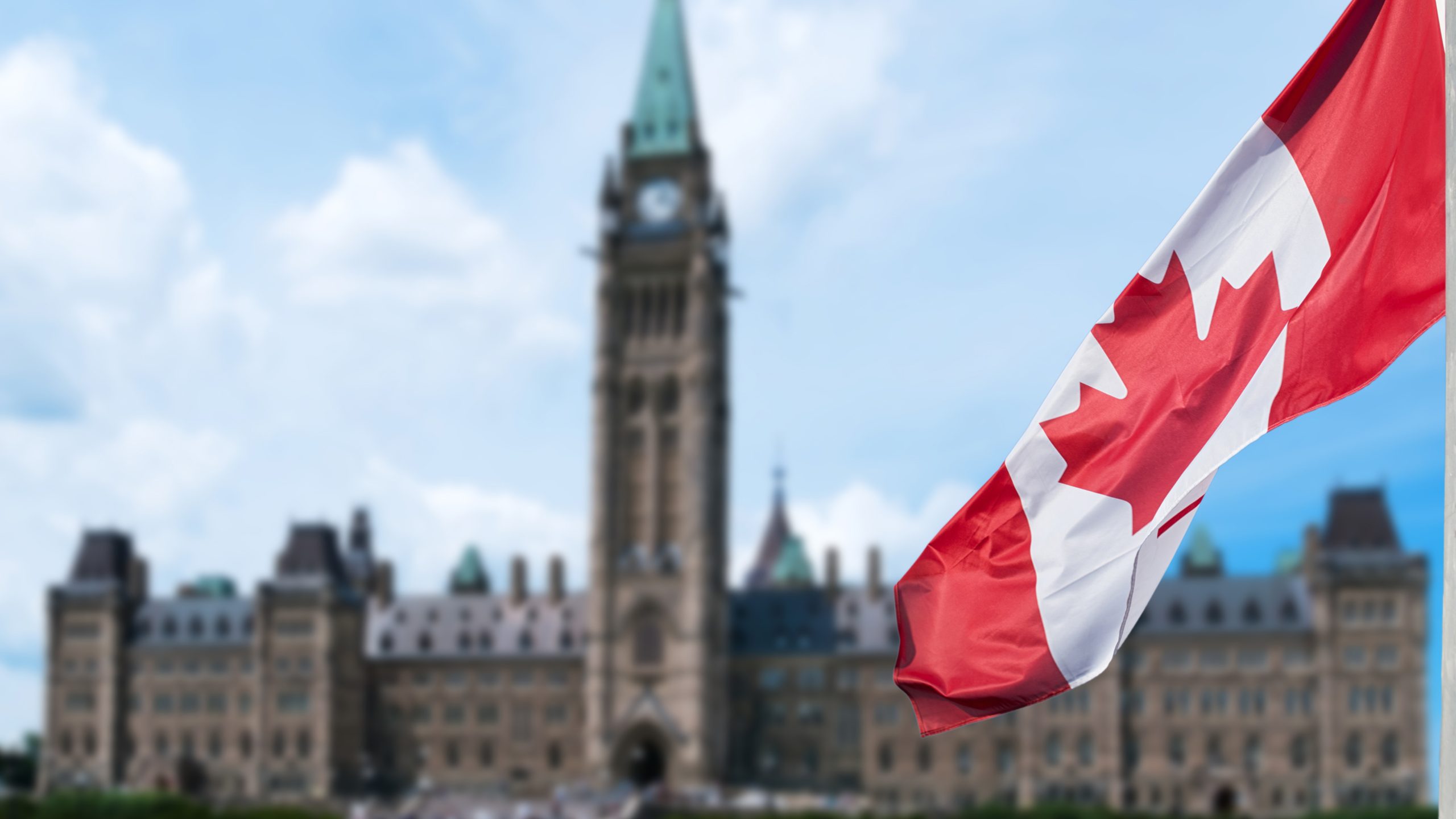 Canadian flag waving with Parliament Buildings hill in the background Ottawa,Ontario, Canada