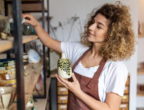 Small business owner standing and looking at a shelf