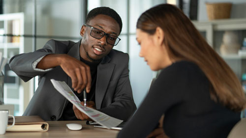 A man pointing at a paper being held by a woman